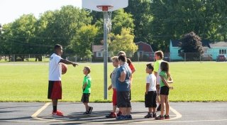 Student working with local youth on basketball court