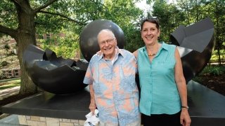 Dick Brush '52 with Cathy Tedford in front of the sculpture BirthIV
