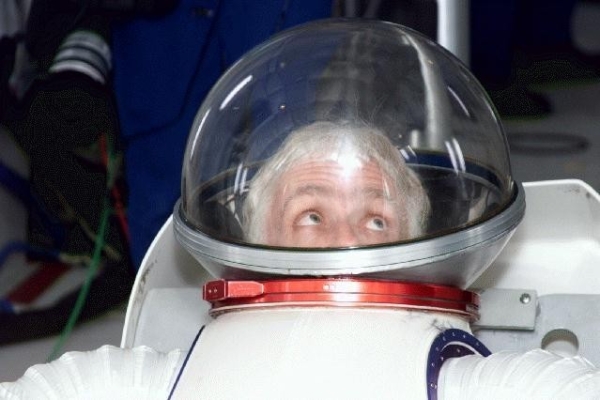Dean Eppler, wearing a white NASA suit, looks up. 