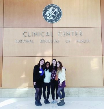 A photo of a group of students standing under the National Institute of Health's Clinical Center sign. 