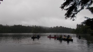 Boats back in the water after a long portage immersed in inclement weather.