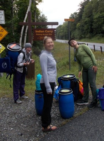 Midway through our portage from Lower Saranac to Stony Creek Pond via Indian Carry. Pickle barrels line the highway as Ruby, Arianna, and Campbell prepare to cross.