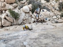 A photo of students scaling the side of a rocky cliff.