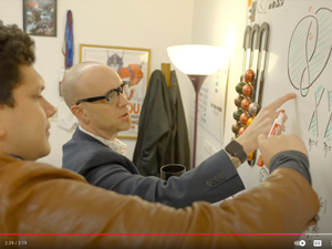 Dan Look and Eduardo Puerto examine a math problem on a whiteboard.