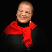 A woman wearing black top and red scarf