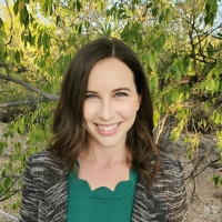 Photo of White woman with brown hair in green top and grey jacket