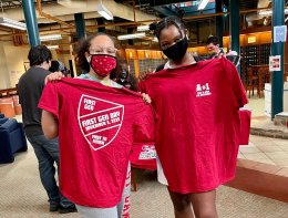 Two Saint Lawrence University students hold up t-shirts during National First Generation Celebration Day.