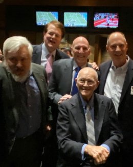 Coach Leet sitting with four former athletes standing behind him.