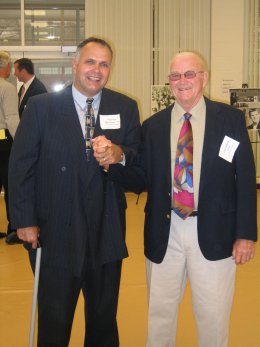 Two men stand holding hands.