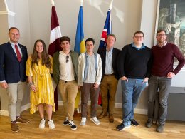 Saint Lawrence students, studying abroad in London, stand in front of the flags of Latvia, Ukraine, and the United Kingdom at the Embassy of Latvia in London, England.