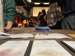 A close up of Apothecary chocolate bars with fliers about chocolate and students in the background. 