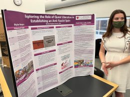 Skylar stands next to a poster displaying her research