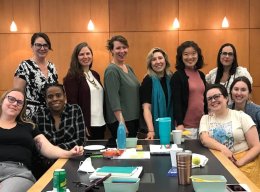 A group of Saint Lawrence faculty members stand near a long table while attending a professional development retreat.