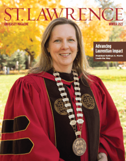 The winter 2023 edition of the Saint Lawrence magazine that features President Morris on the cover wearing scarlet and brown regalia and a medallion, outside on a sunny fall day. Bright orange leaves cover the trees in the backgrounf.