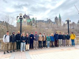 STUDENTS AND JOSEPH JOCKEL STANDING ALONG THE RIDEAU LOCKS, WITH PARLIAMENT IN THE BACKGROUND