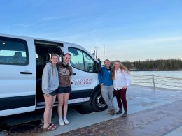 two female students and two female faculty standing next to SLU Van on fairy