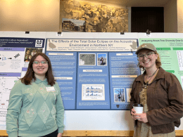 two female students smiling while presenting their poster