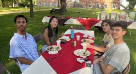 College students sitting at outdoor dining table with food