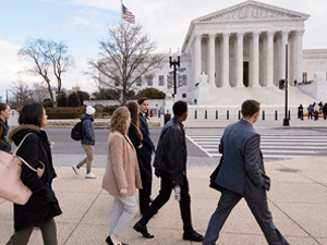 A group of Saint Lawrence students, wearing professional attire, walk in front of a government in Washington.
