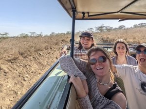 Four Saint Lawrence students smile big as they take a tour through tall grass in Kenya.