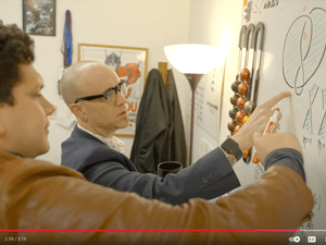 Dan Look and Eduardo Puerto examine a math problem on a whiteboard.