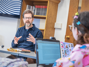 Adam Harr, speaks to a student in a classroom.