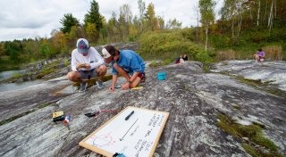 Two students conduct research during a geology lab at Hart's Falls near campus.