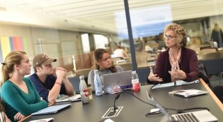 Professor Liz Regosin sits at the head of a discussion table, leading a conversation among her students.