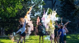 Students throwing colored chalk into the air