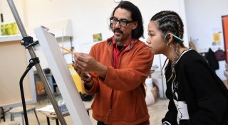 A student collaborates with her professor as she begins the sketch for a painting.