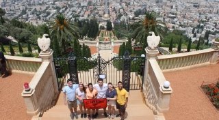 Six students hold a red Saint Lawrence University in front of an impressive city view while studying abroad. 