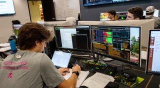 A student examines data on several computer screens in the Bloomberg Finance Lab. 