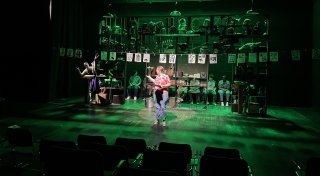 A woman at a lectern bathed in green light