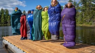 Laurentians jumping in sleeping bags on a dock