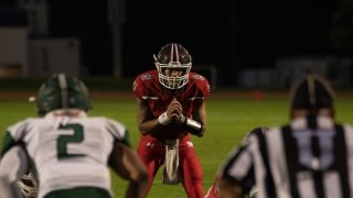 A Saint Lawrence football player, wearing a red jersey and helmet, prepares for the play on the football field.
