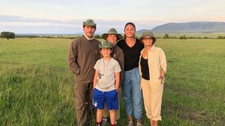 A family of five individuals gather for a photo on a grassy plain in Kenya. 