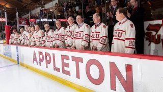 Donors to Appleton Arena lineup on the home bench in custom jerseys.