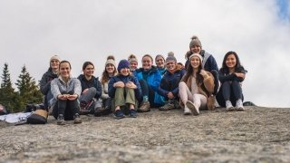 Twelve Saint Lawrence students sit on a rock at the summit of Balanced Rock, Lake Placid, New York. 
