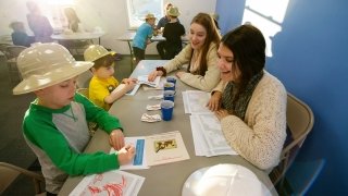 Two students work on a drawing project with two elementary school children. 