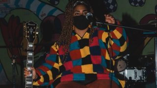 A Saint Lawrence student with their guitar on stage during an open mic night at the live music venue on campus.