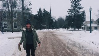 A prospective students stands on a snow-covered path on the Saint Lawrence University dorm room.