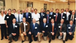 Group of alumni in suites staged for a picture.