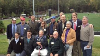 A group of people staged for a photo with field in the background.