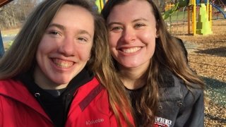 Two students stand next to each other and smile for a selfie. 
