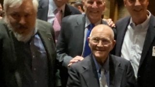 Coach Leet sitting with four former athletes standing behind him.