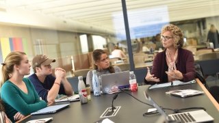 Professor Liz Regosin sits at the head of a discussion table, leading a conversation among her students.
