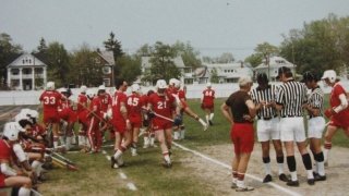 Don Leet having a pre-game conversation with officials. Lacrosse team can be seen in the background.