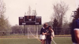 Scoreboard reads 12-11 in Saints favor with people in the foreground.