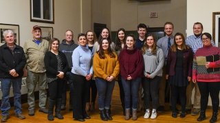 A group of 20 Saint Lawrence students stand with their professors as they receive an award.