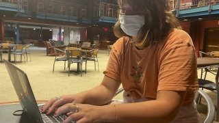 A student sitting inside the Student Center and working on her computer.